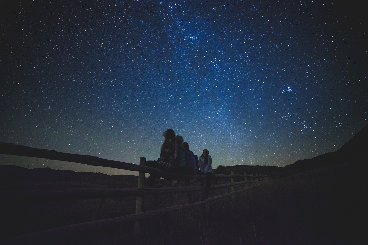 A number of people sitting on a fence, enjoying the Sedona Star Gazing Tour